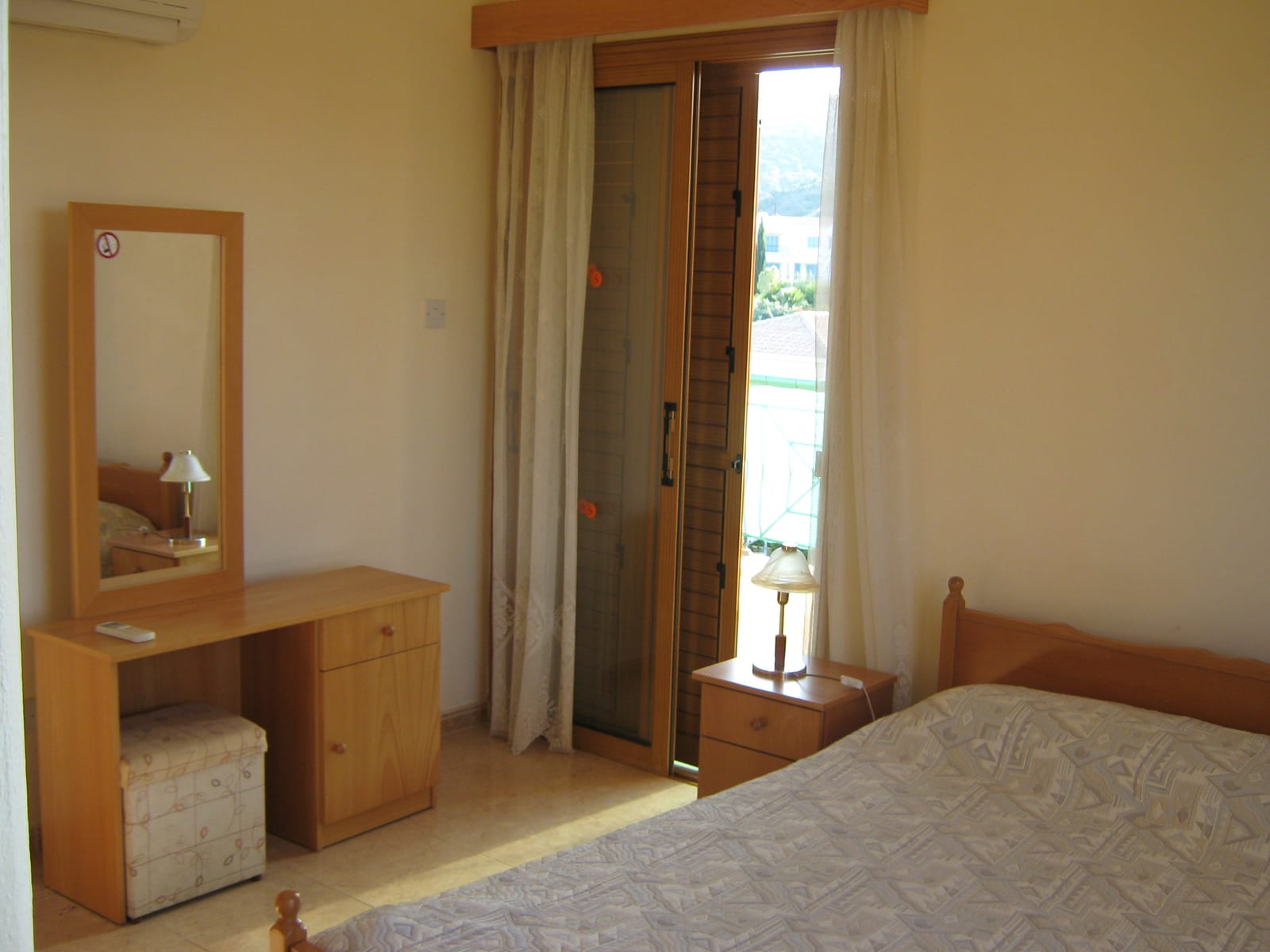 Double bedroom with a dressing table, mirror and a door onto the balcony