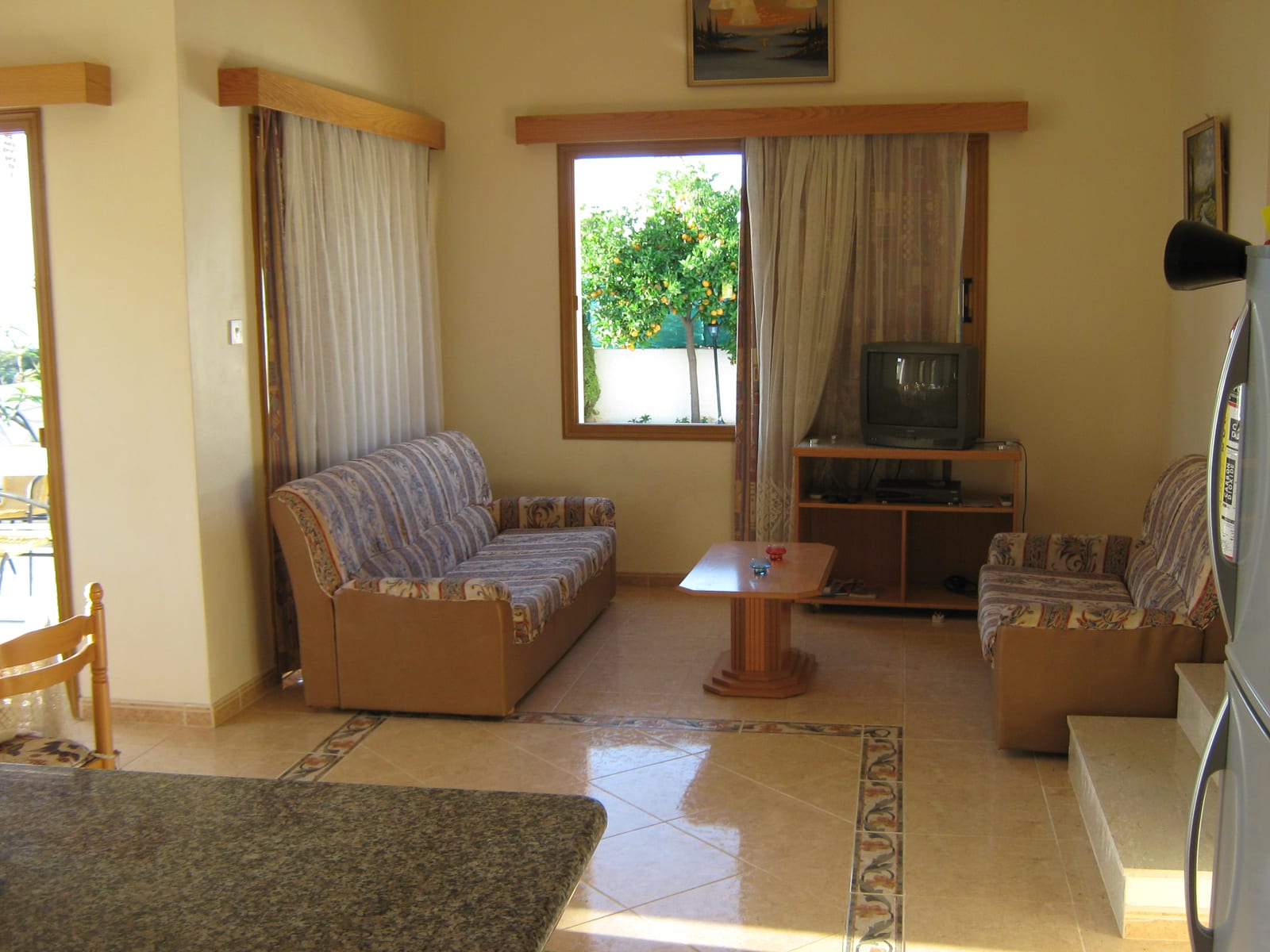The living room with two sofas, a low table and a window onto the orange tree