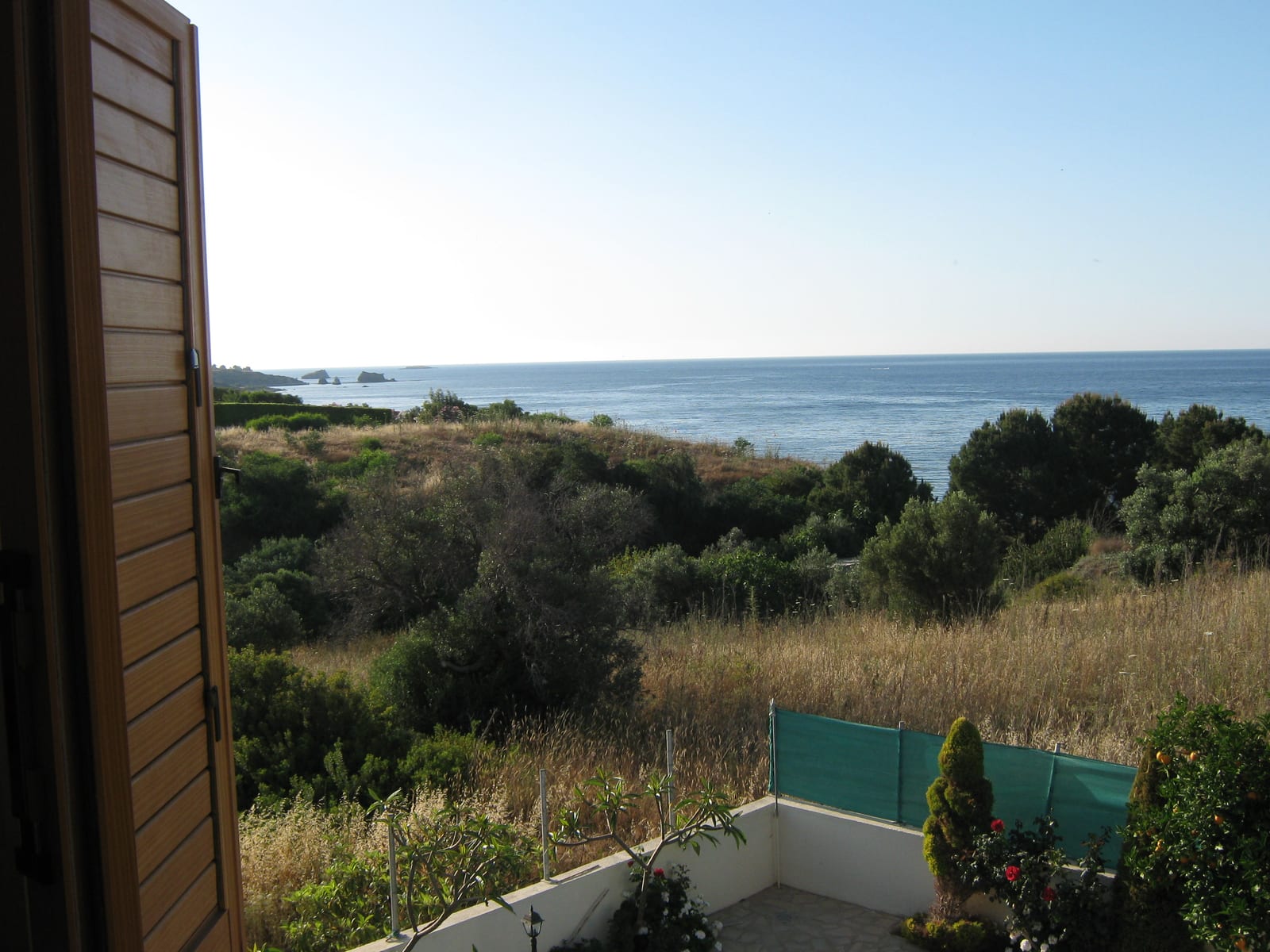 View from a bedroom window across scrubland to the sea and offshore rocks